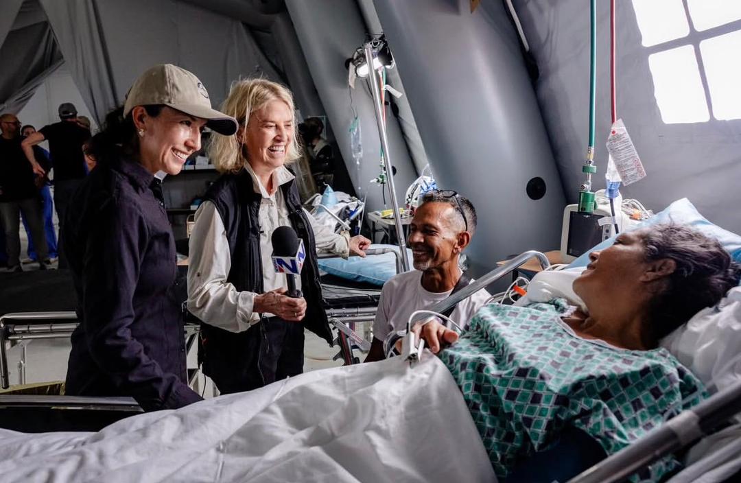 Relief workers speaking with patients and their families in a field hospital ward